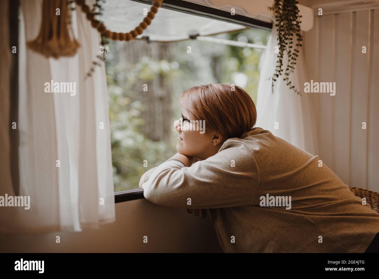 Giovane donna allegra e sognante in una finestra furgone in natura. Foto Stock