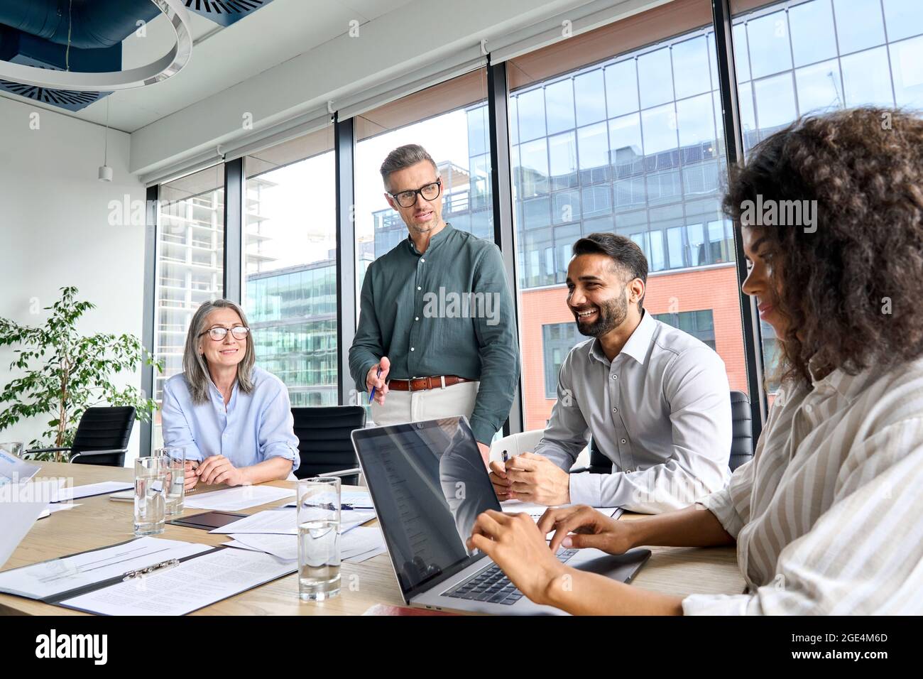 Il leader maschile del CEO parla con i partner al meeting in sala riunioni in un ufficio moderno. Foto Stock
