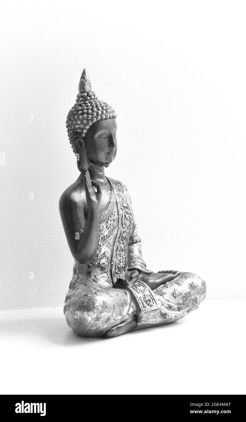 Statua di Buddha posta al centro dell'immagine su sfondo bianco. L'immagine è in bianco e nero Foto Stock