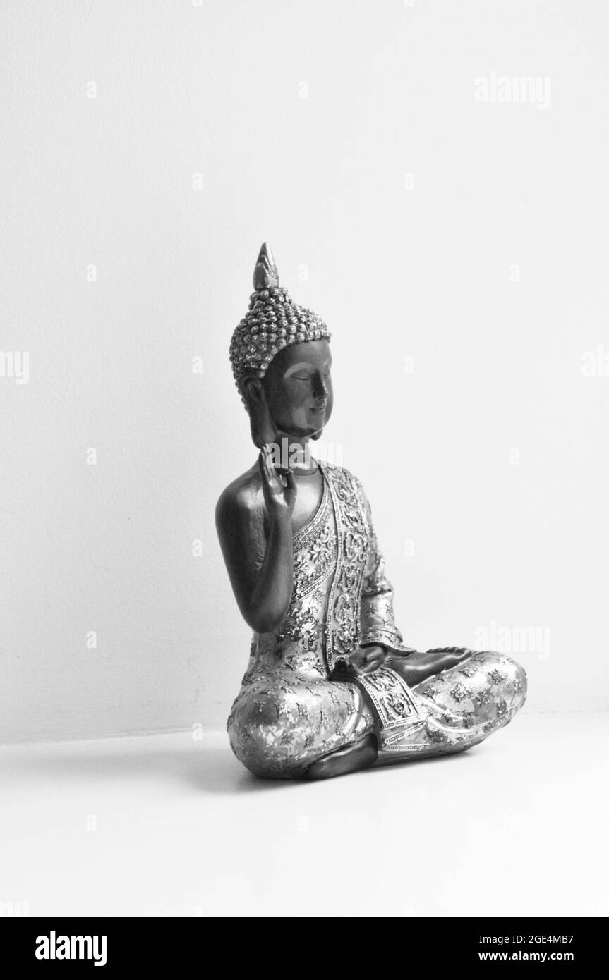 Statua di Buddha posta a destra dell'immagine su sfondo bianco. L'immagine è in bianco e nero Foto Stock