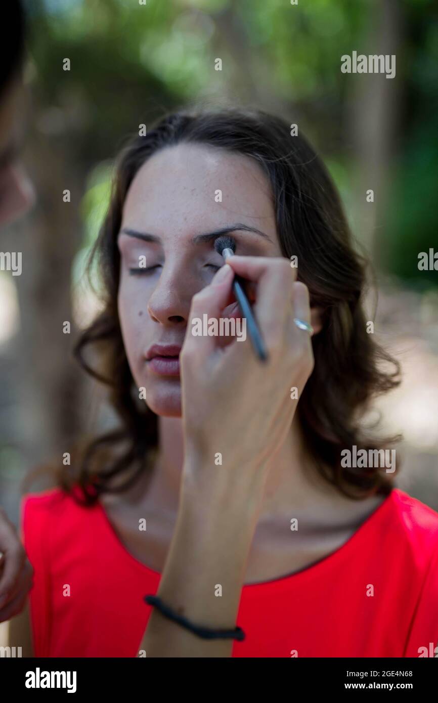 Closeup shot di una giovane donna che ottiene il suo makup con gli occhi chiusi all'aperto Foto Stock
