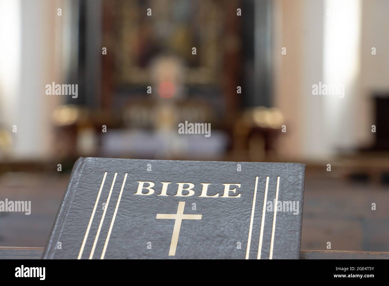 La Bibbia sulla tavola di una panchina di preghiera nella chiesa con un altare, da vicino. Foto Stock