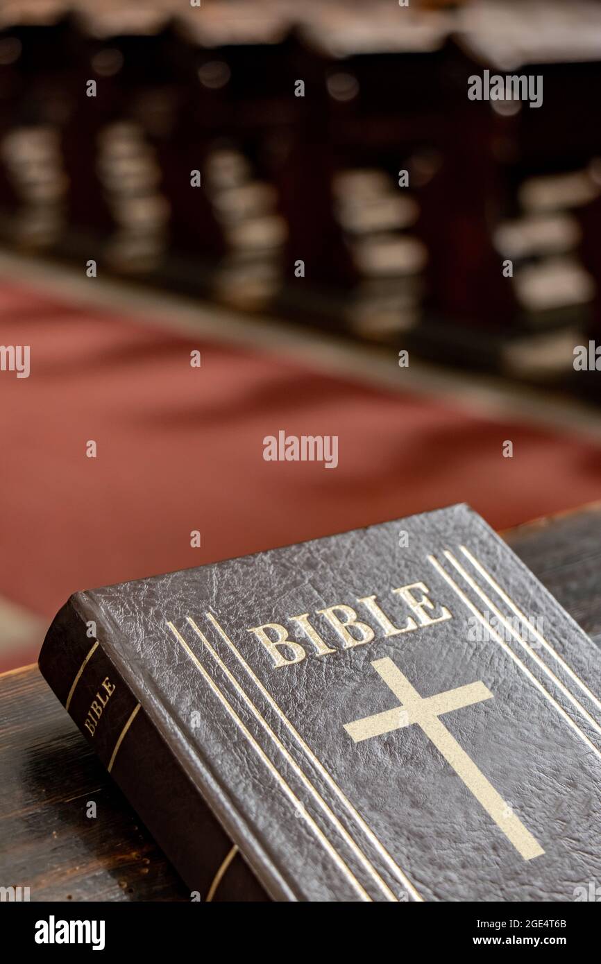 La Sacra Bibbia sulla tavola di una panchina di preghiera nella chiesa. Foto Stock