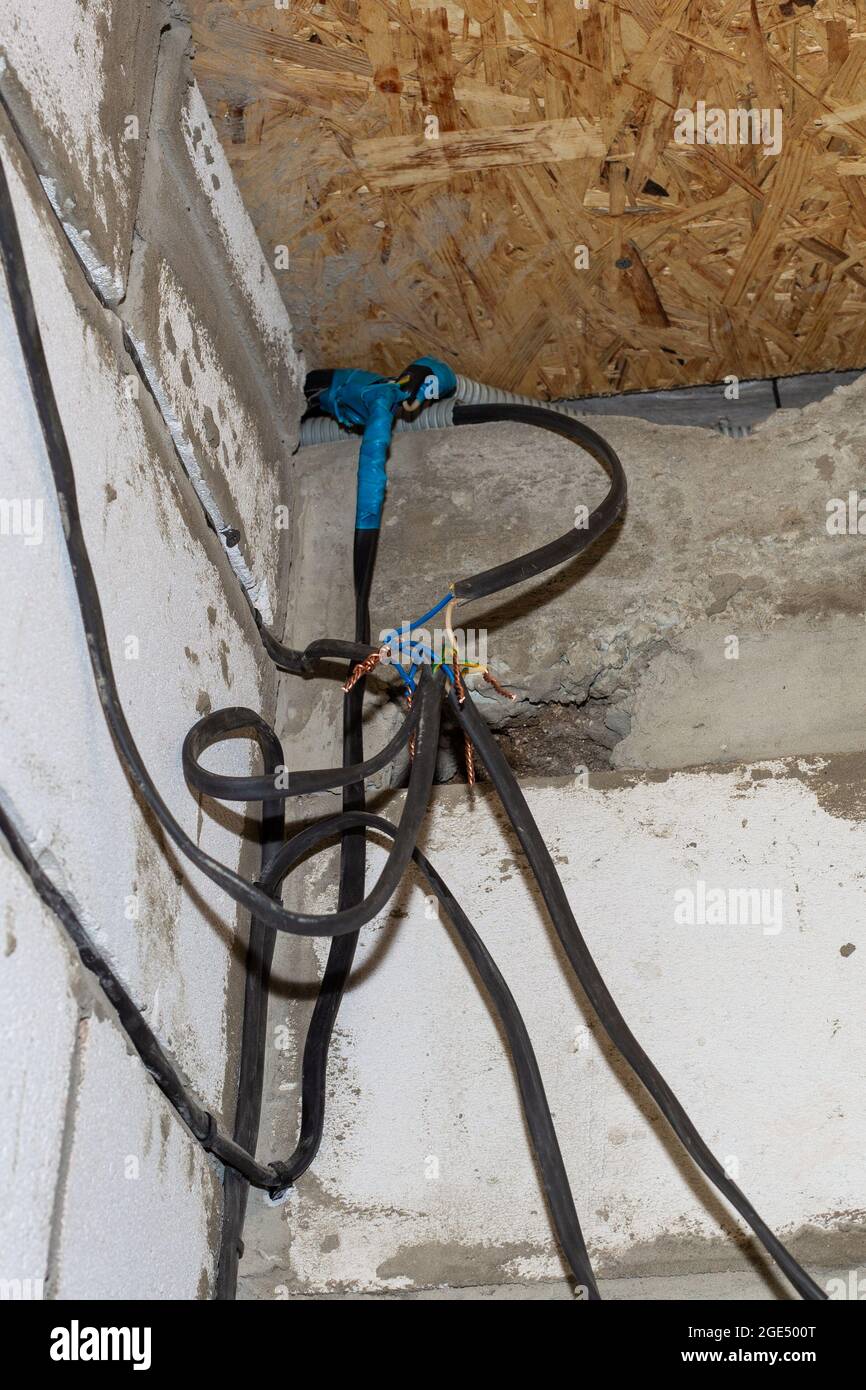 Collegamento di fili sullo sfondo di una parete in una casa in costruzione.  Attorcigliamento, saldatura, saldatura di cavi elettrici Foto stock - Alamy