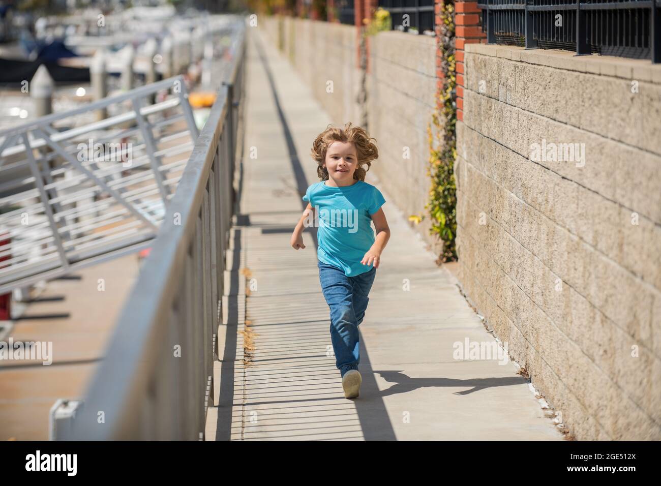 Bambino ragazzo attivo divertirsi a correre sul lungomare in estate, attività Foto Stock