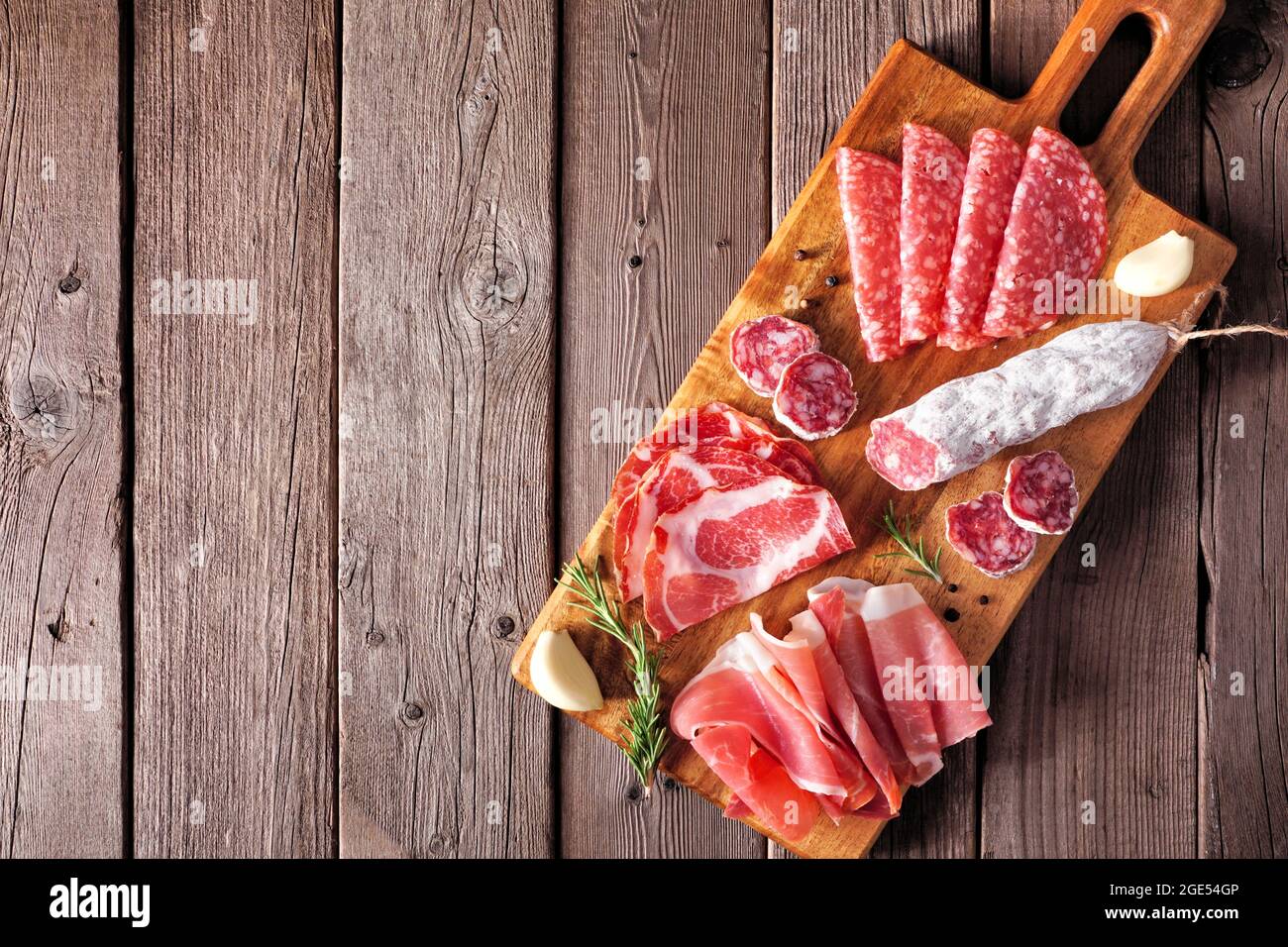 Piatto di antipasti con salsiccia, prosciutto, prosciutto e salame. Vista dall'alto su una tavola di servizio su uno sfondo di legno. Foto Stock