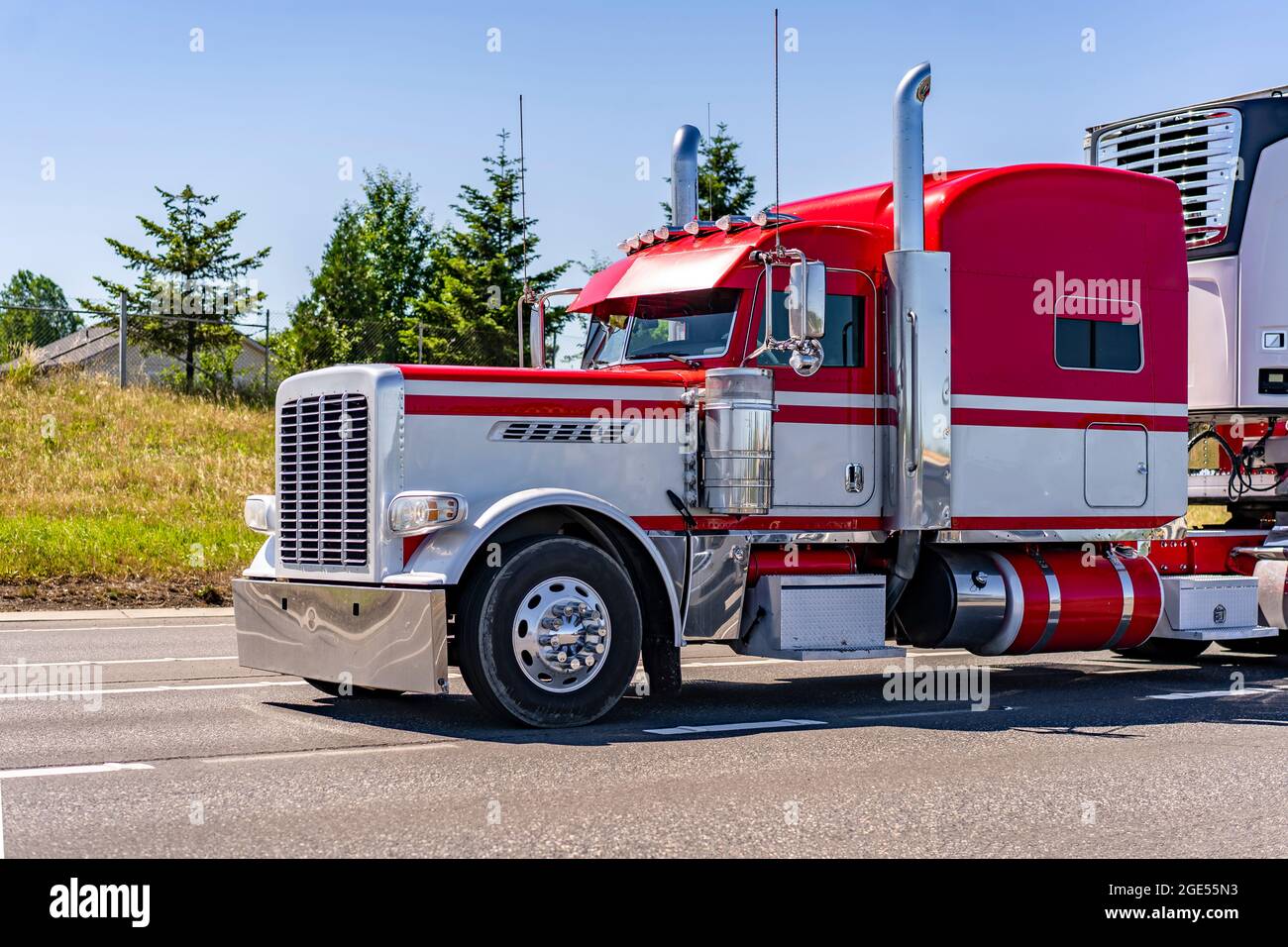 Rosso e bianco Big RIG Long HAUL Classic American semi Truck con dettagli cromati trasportatore carico congelato in frigorifero semi-rimorchio in esecuzione Foto Stock