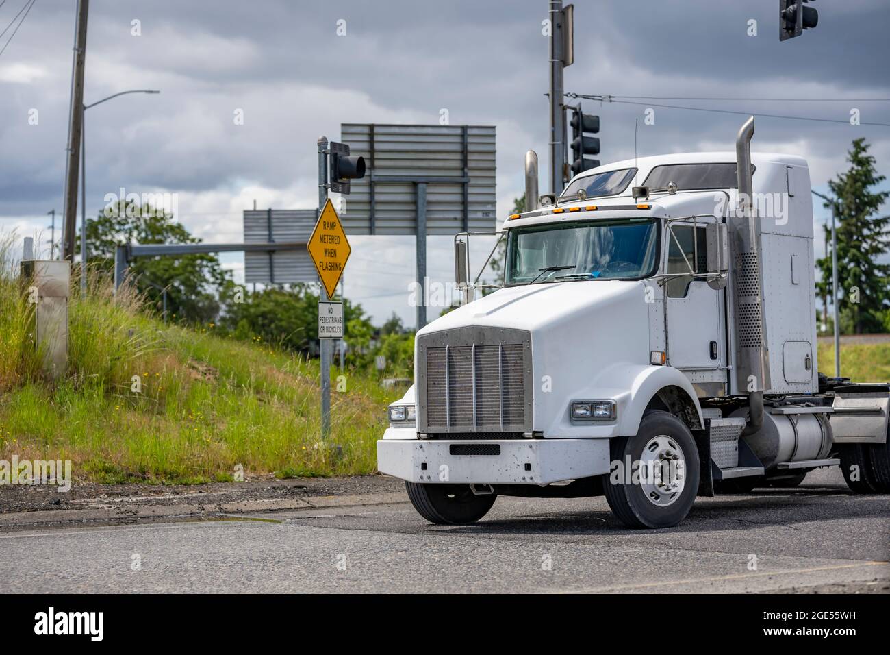 Potente trattore per semirimorchio con cofano bianco Big RIG di grado  industriale, con cinque ruote che girano sull'uscita autostradale e che si  porta al magazzino per il pick-up caricato Foto stock -