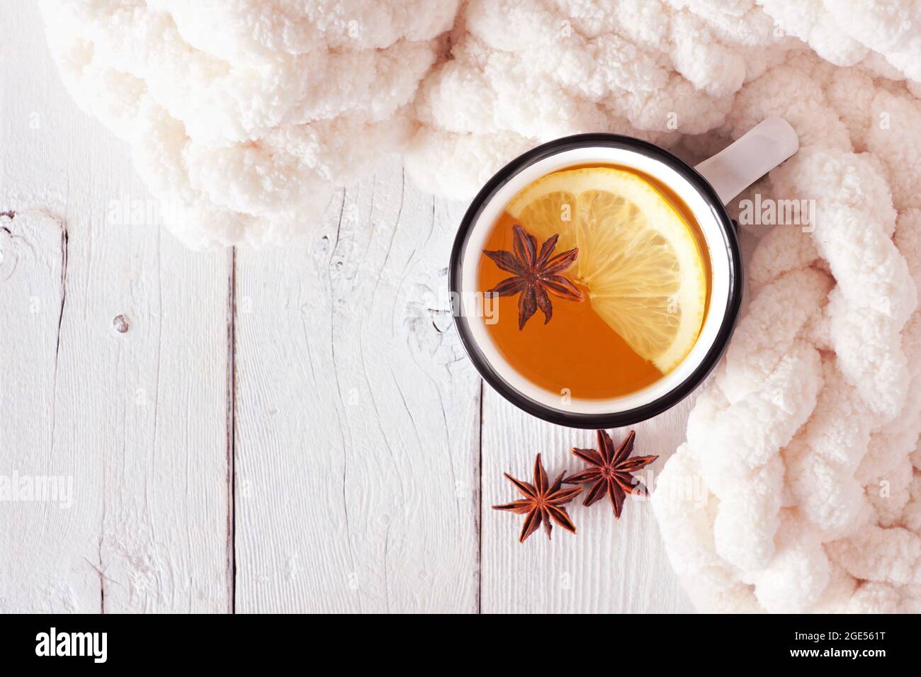 Tè alle spezie al limone, vista dall'alto su uno sfondo di legno bianco con coperta. Accogliente tema autunno o inverno. Foto Stock