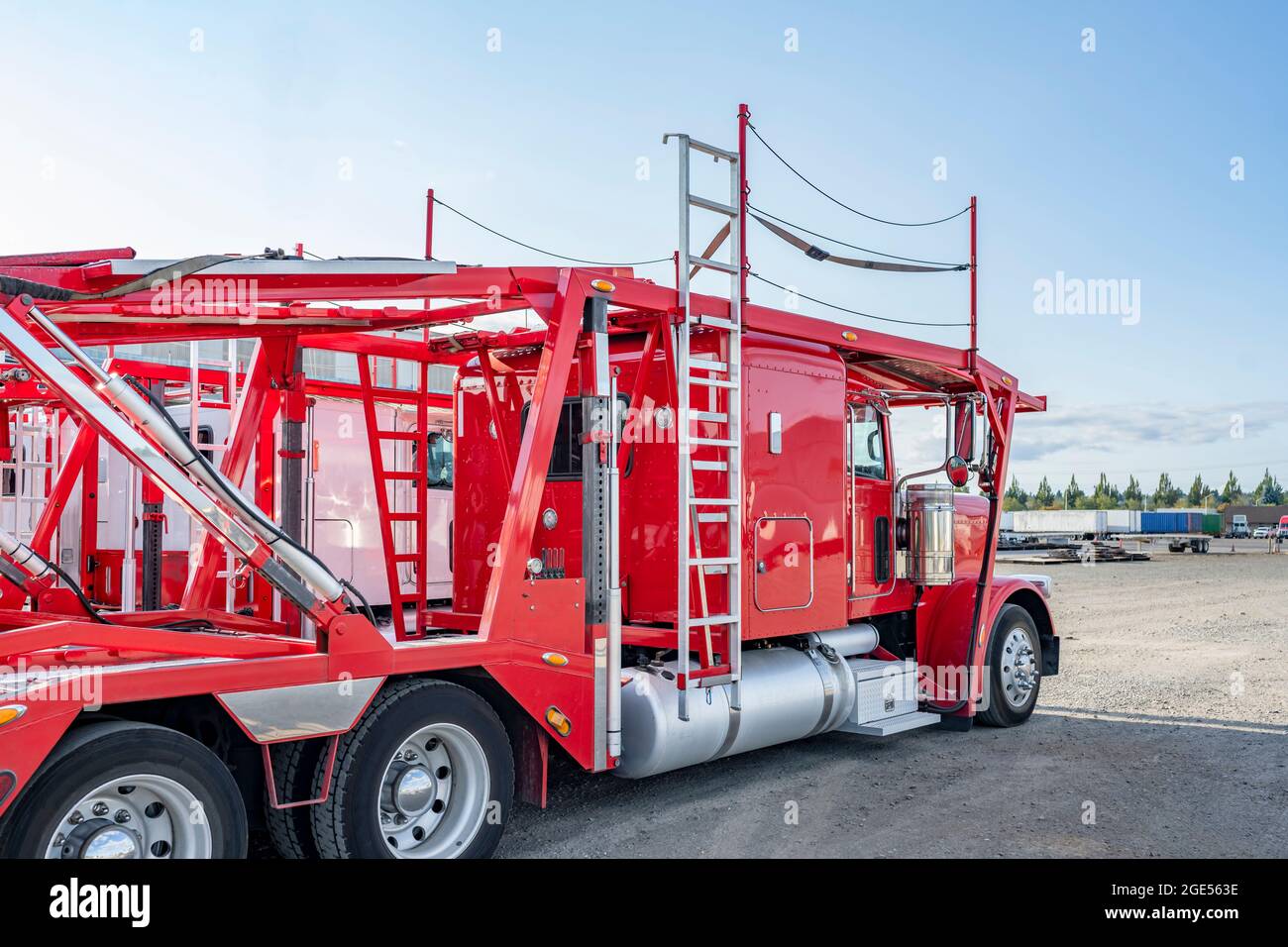 Trattori semirimorchi con cabina corta PRO Big RIG Classic rossi e bianchi con semirimorchi modulari idraulici a due livelli per autotrasportatori in piedi sulla wa Foto Stock