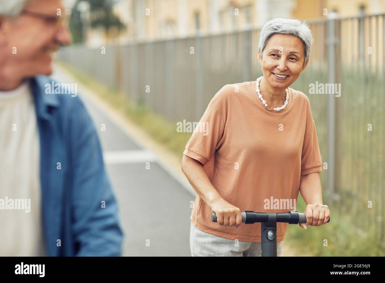 Ritratto di una coppia moderna che cavalca scooter elettrici all'aperto in una splendida città, spazio copia Foto Stock