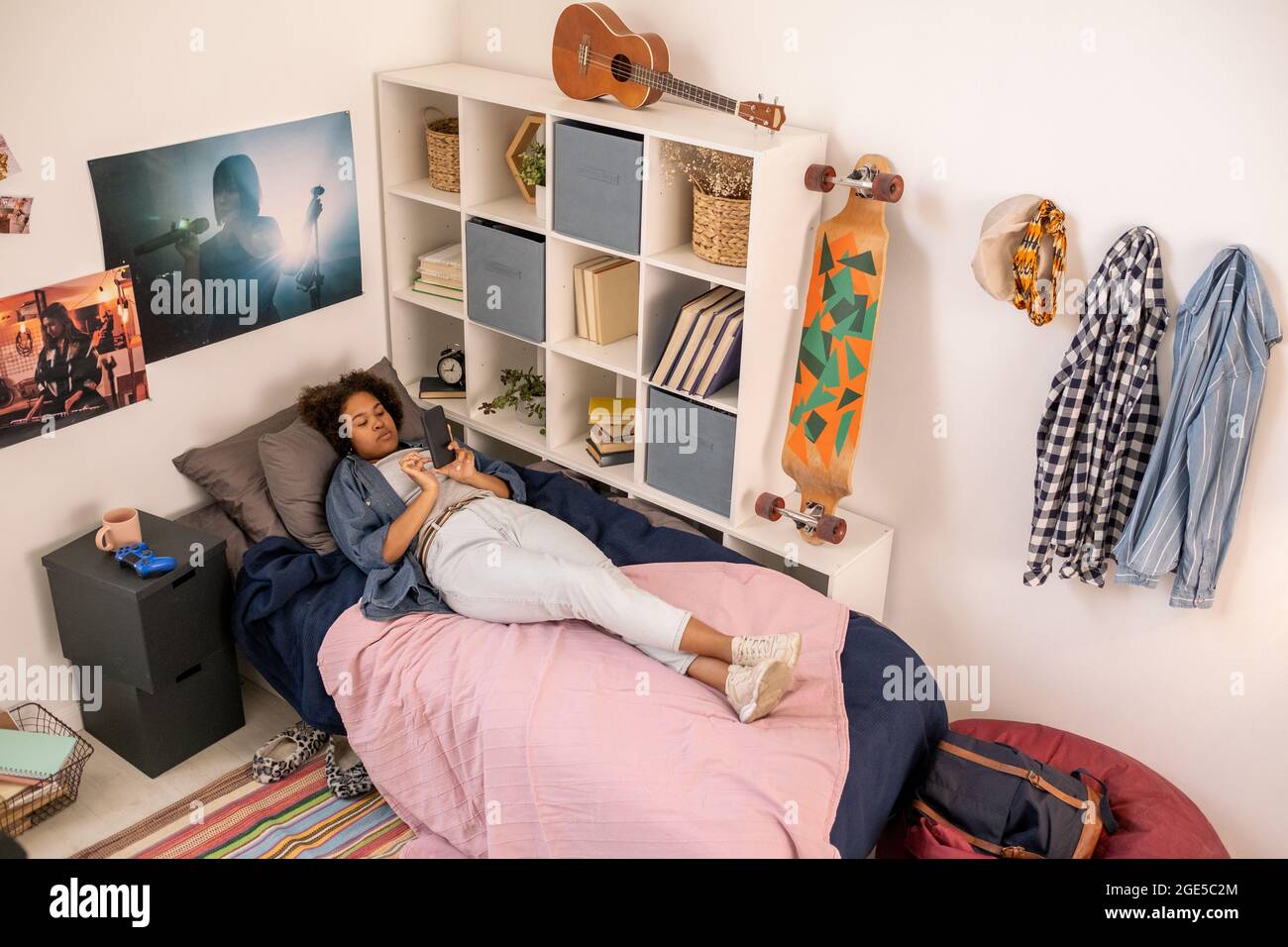 Giovane donna africana con smartphone che si rilassa a letto e scorre attraverso le cose online Foto Stock