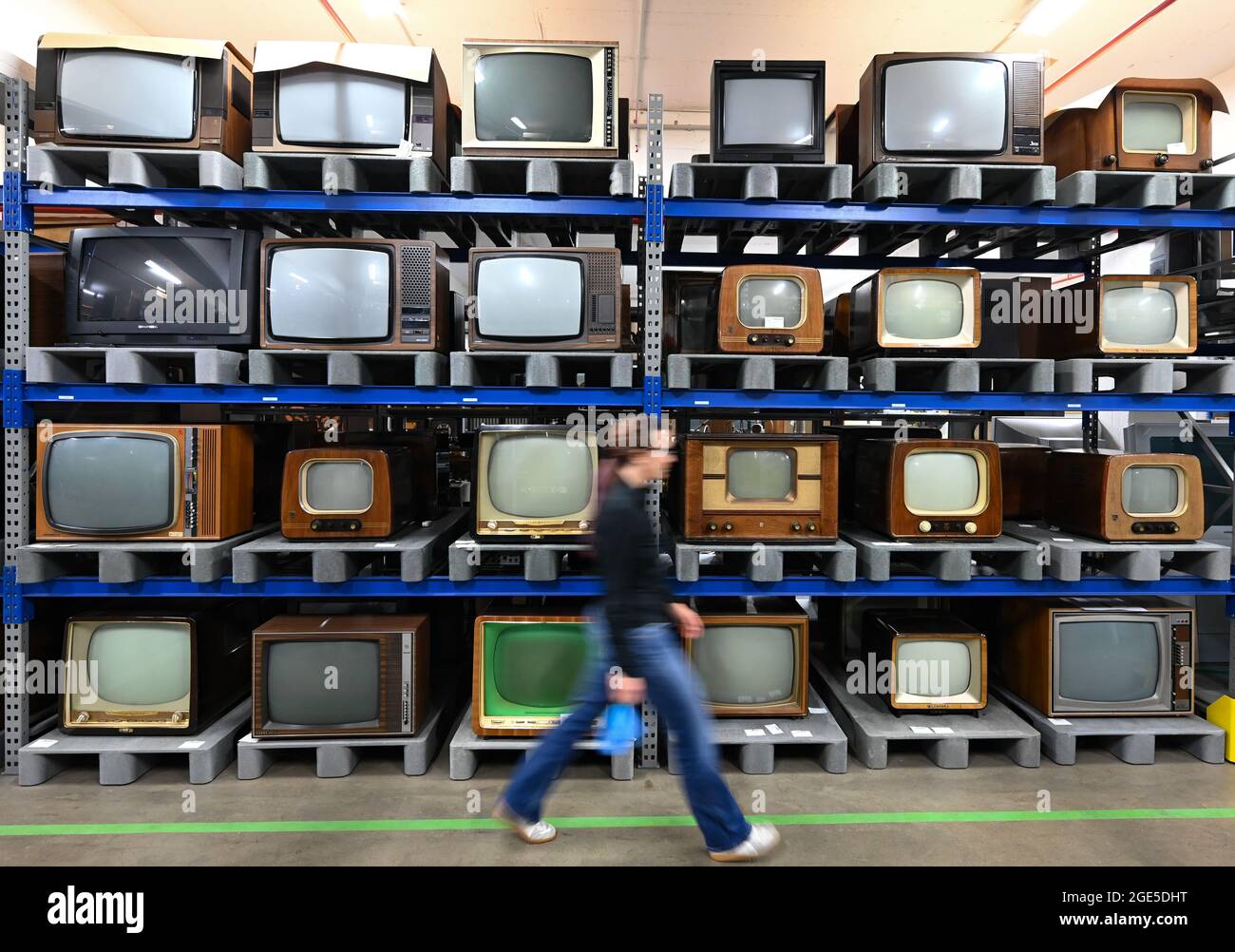 Heusenstamm, Germania. 10 agosto 2021. Tina Kubot, conservatrice della storia dei media, passa accanto a un'alta serie di televisori nel Museo della comunicazione - Collezioni (scatto a bassa velocità). Il 22 agosto 1931, il primo televisore elettronico è stato presentato ad una fiera tecnologica di Berlino. (A dpa 'la madre di tutti i gawkers: La televisione elettronica ha 90 ° compleanno') credito: Arne Dedert/dpa/Alamy Live News Foto Stock