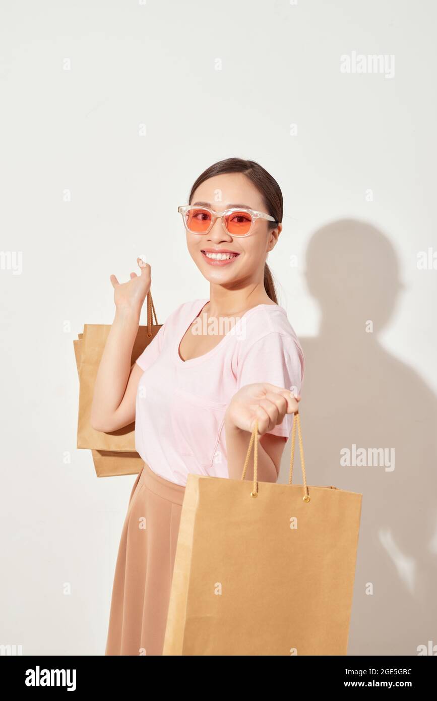 Bella giovane donna asiatica che tiene una borsa della spesa, sorridente con un buon umore, shopping allegro in Holiday al centro commerciale Foto Stock
