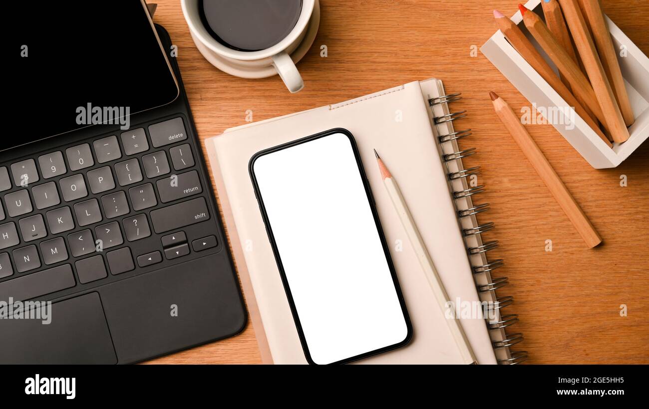 Mockup di smartphone schermo bianco e tablet, spazio in ufficio in primo piano nella vista dall'alto, sfondo in legno texture, oggetti dispositivo wireless Foto Stock