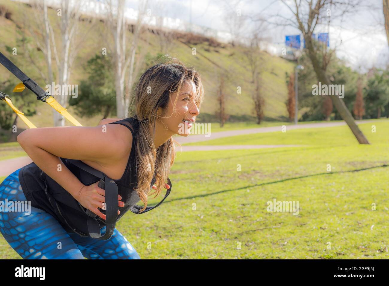 Sportivo atletico facendo esercizi di schiena squatting con cinghie fitness. Foto Stock