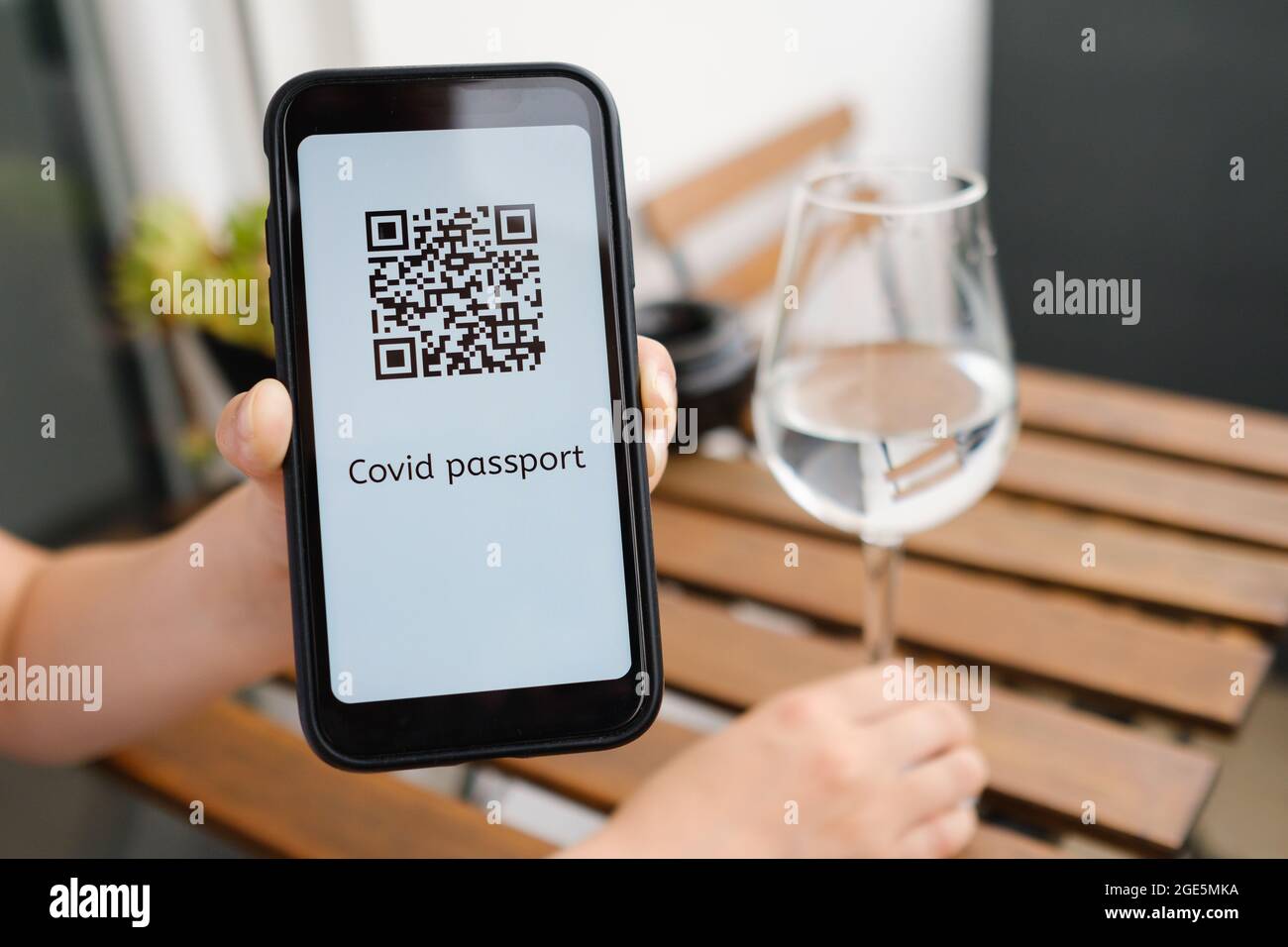 La donna dimostra l'applicazione Covid pass o il passaporto sanitario digitale con codice QR nel telefono cellulare seduto al bar, Foto Stock