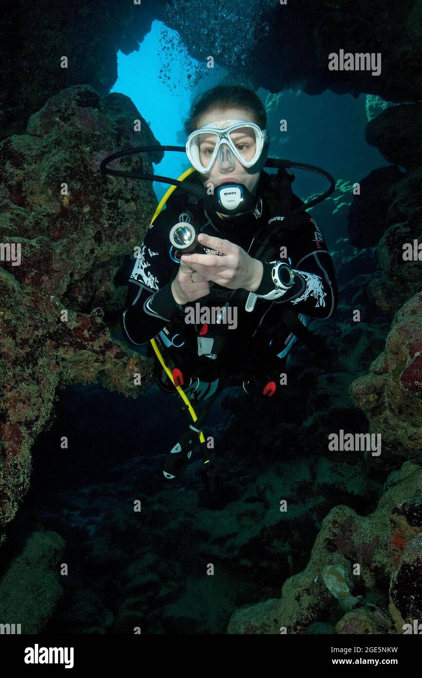 Giovane donna con attrezzatura subacquea si tuffa nella grotta, Mar Rosso, Egitto Foto Stock