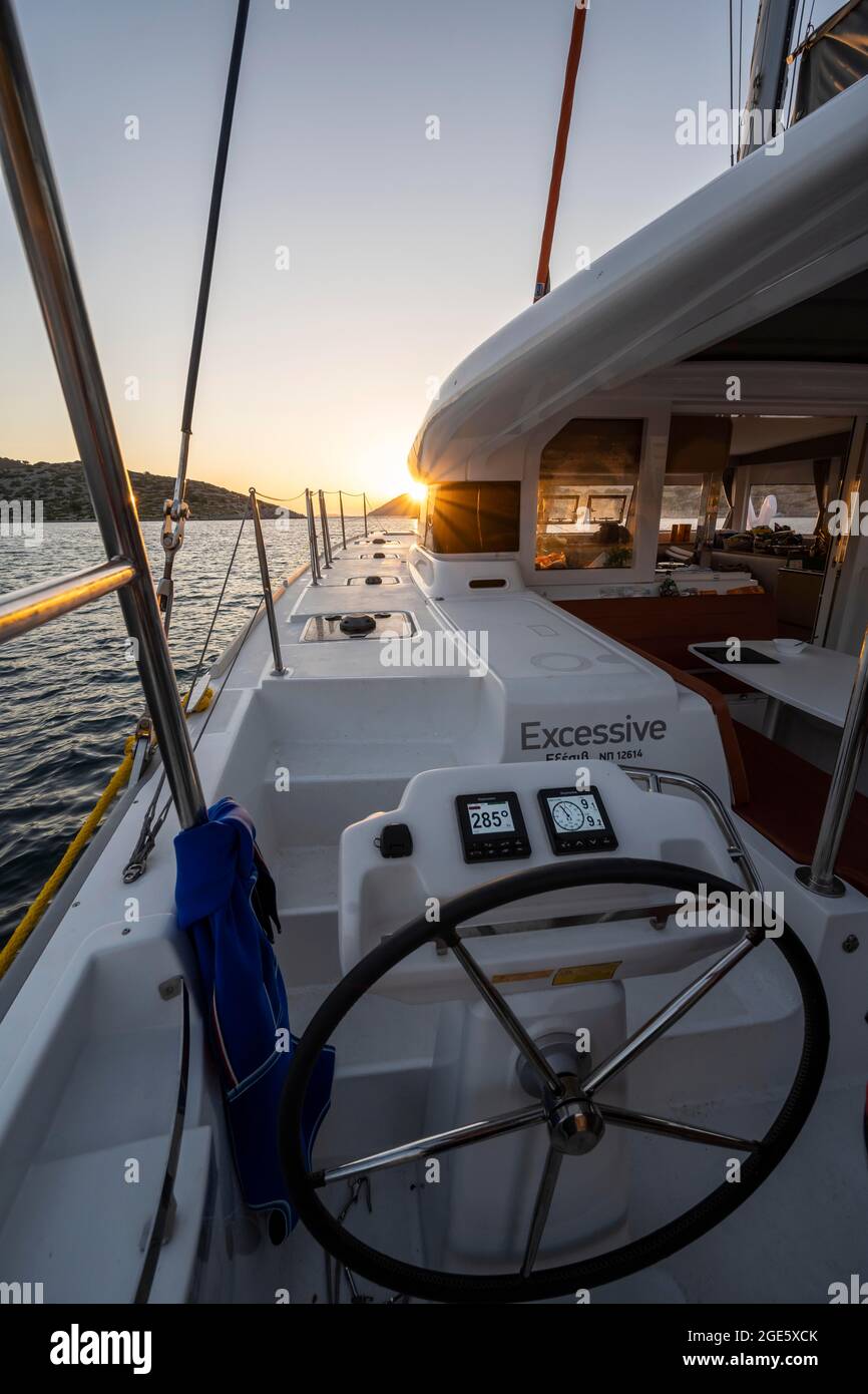 Volante nel pozzetto sul ponte di un catamarano a vela al tramonto, Sun Star, gita in barca a vela, Dodecanese, Grecia Foto Stock