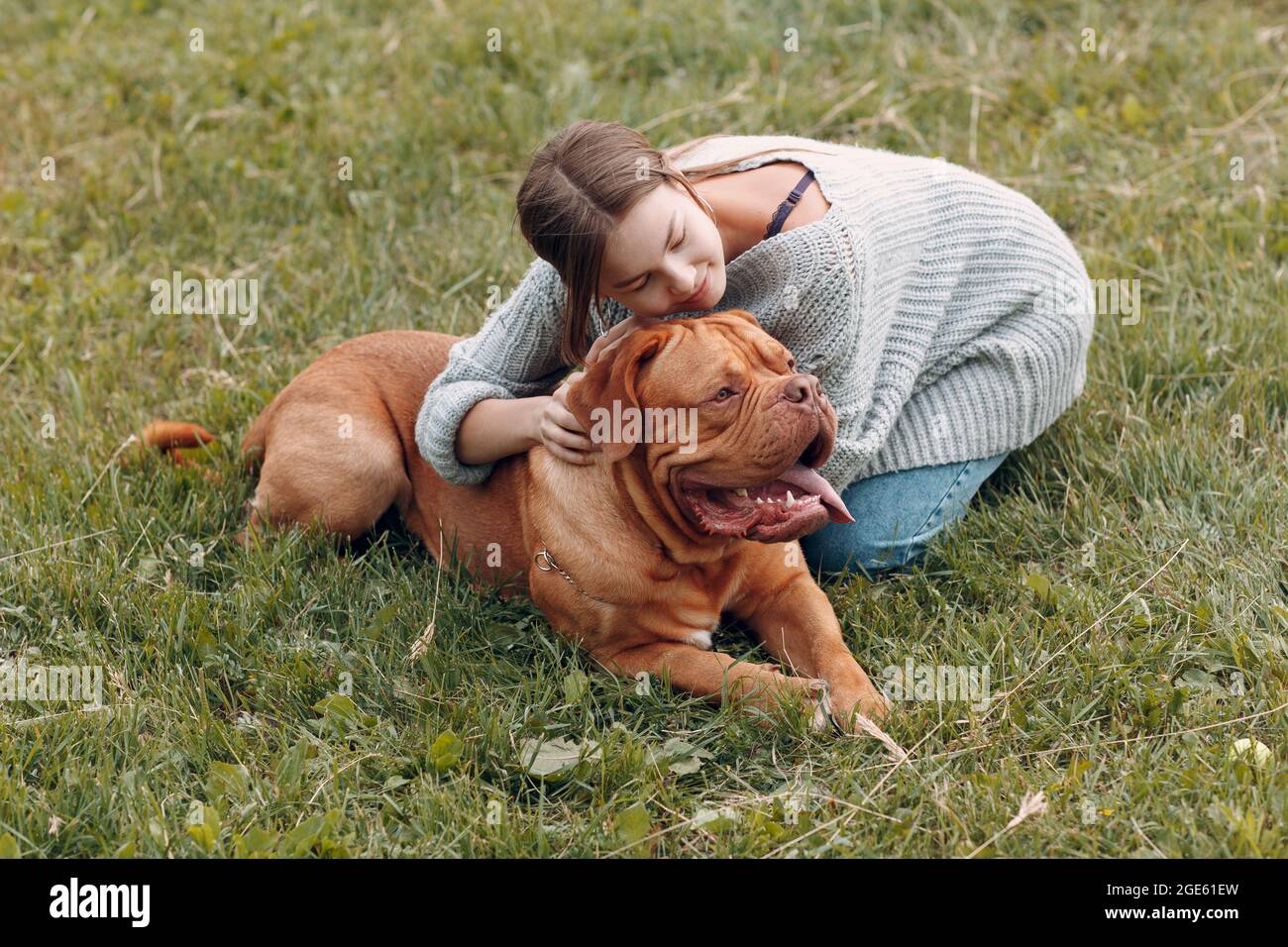 Dogue de Bordeaux o francese Mastiff con giovane donna al prato all'aperto parco. Foto Stock