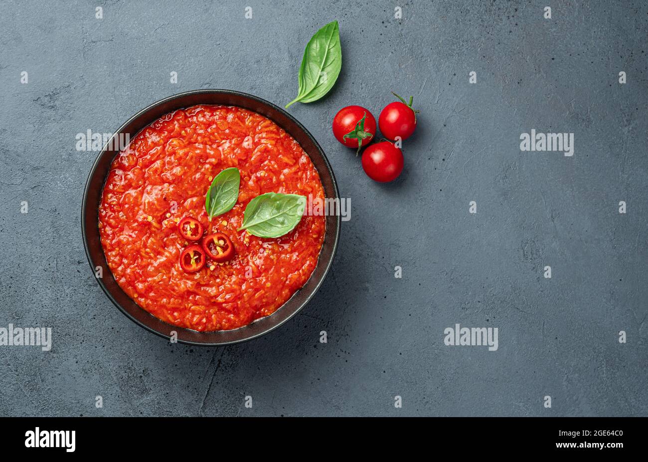 Salsa di pomodoro con pepe e basilico fresco su sfondo scuro. Foto Stock