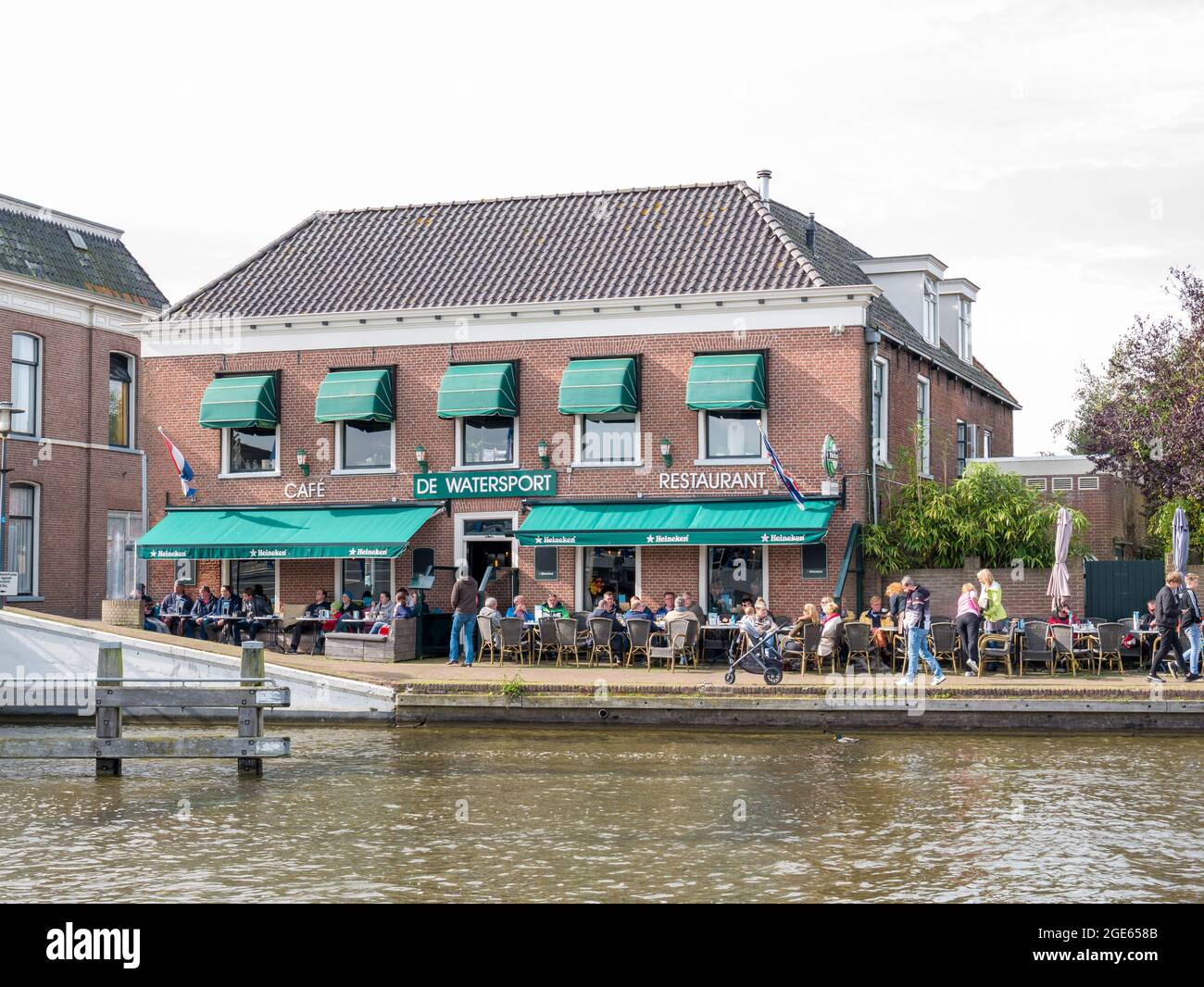 Le persone che godono di una terrazza all'aperto sul marciapiede del ristorante caffetteria del canale EE a Woudsend, Friesland Foto Stock