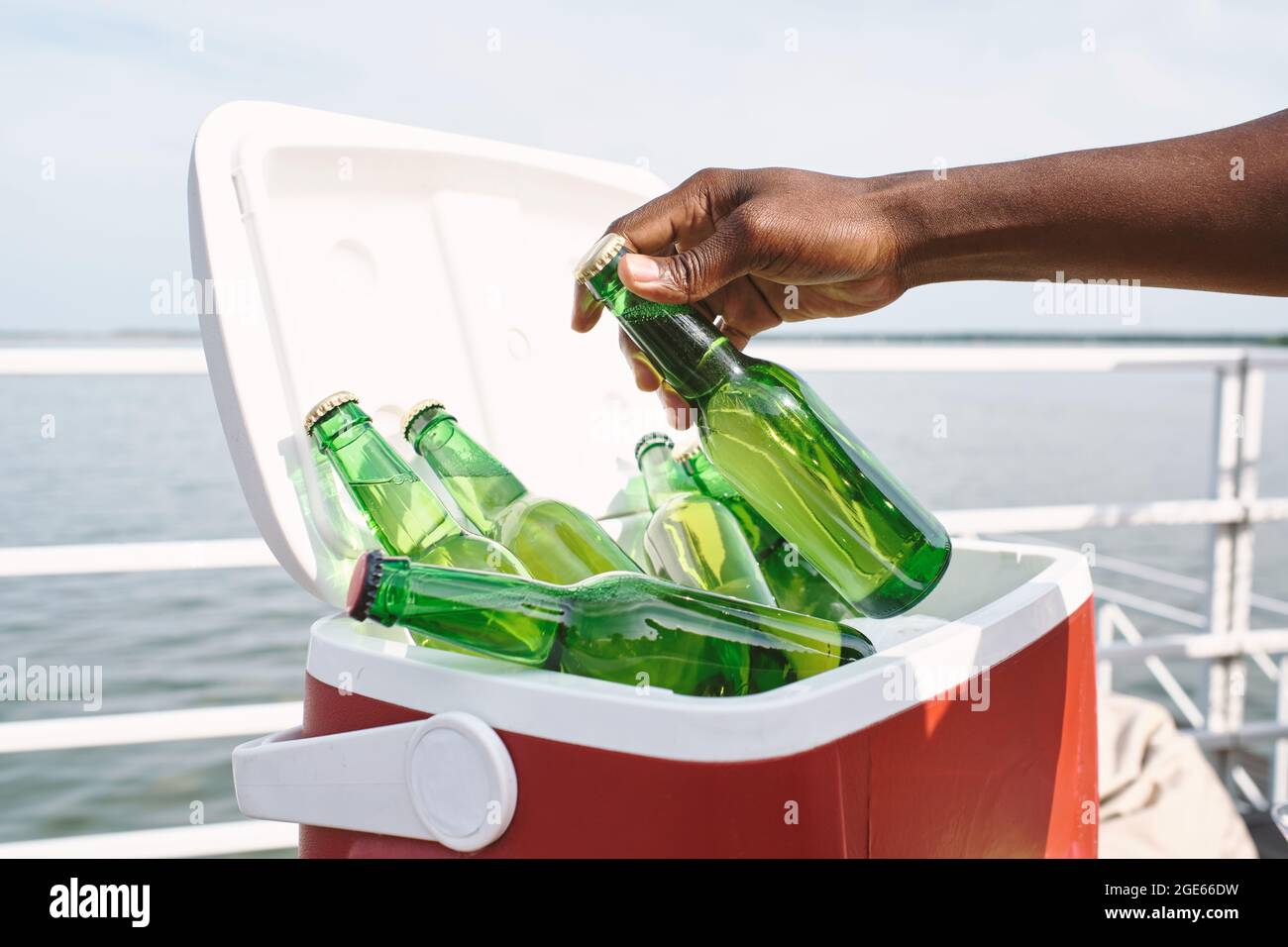 Immagine ravvicinata dell'ospite della festa che prende una bottiglia di vetro di una deliziosa bevanda rinfrescante dalla scatola frigo sullo yacht Foto Stock