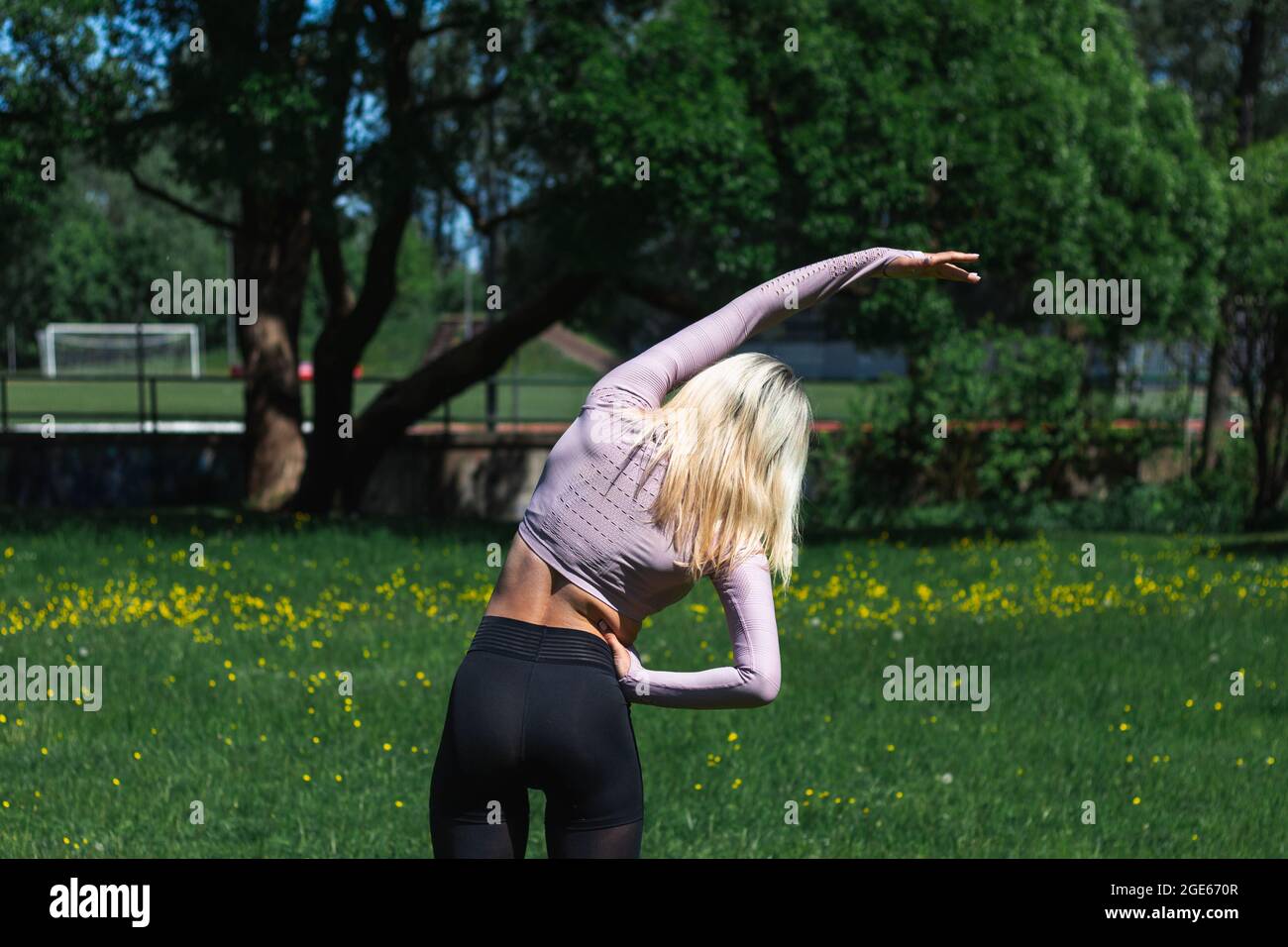 Giovane donna caucasica dai capelli biondi in abbigliamento sportivo sta facendo yoga nel parco. Allenamento all'aperto. Lo yoga pone Foto Stock