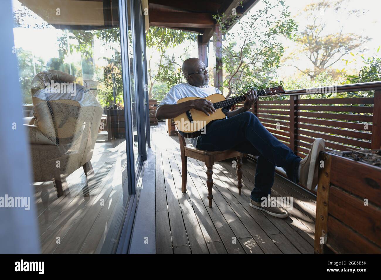 Senior african american uomo sul balcone soleggiato suonando la chitarra Foto Stock