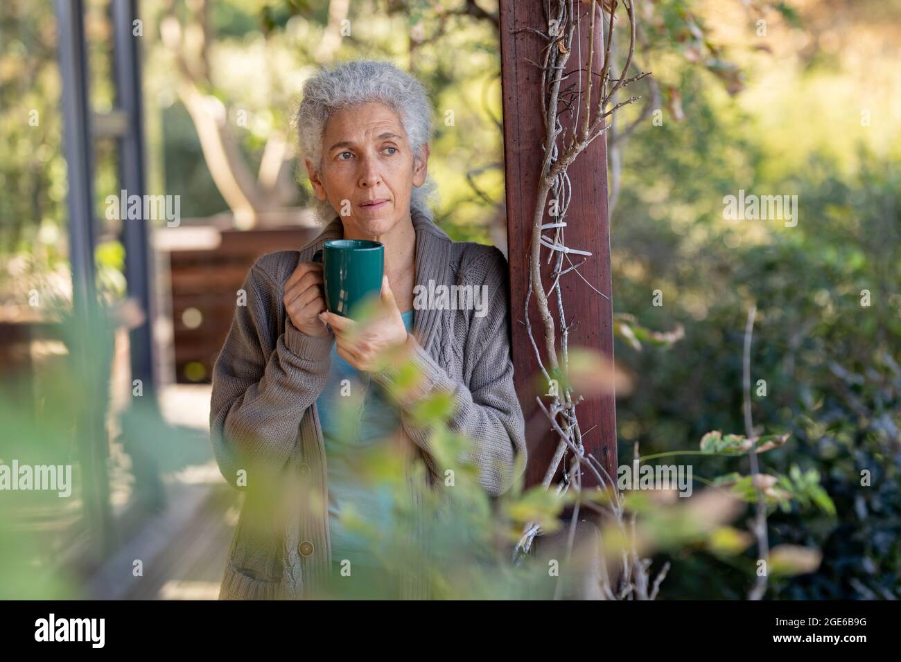 Rilassante donna caucasica senior sul balcone in piedi e bere caffè Foto Stock