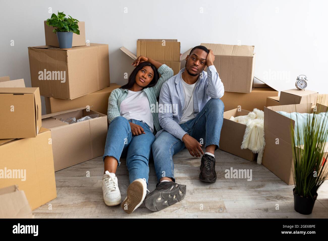 Sad sposi neri esauriti dopo essersi spostati in un nuovo appartamento, seduti tra scatole di cartone e riposati, avendo problemi durante il trasferimento a casa propria Foto Stock
