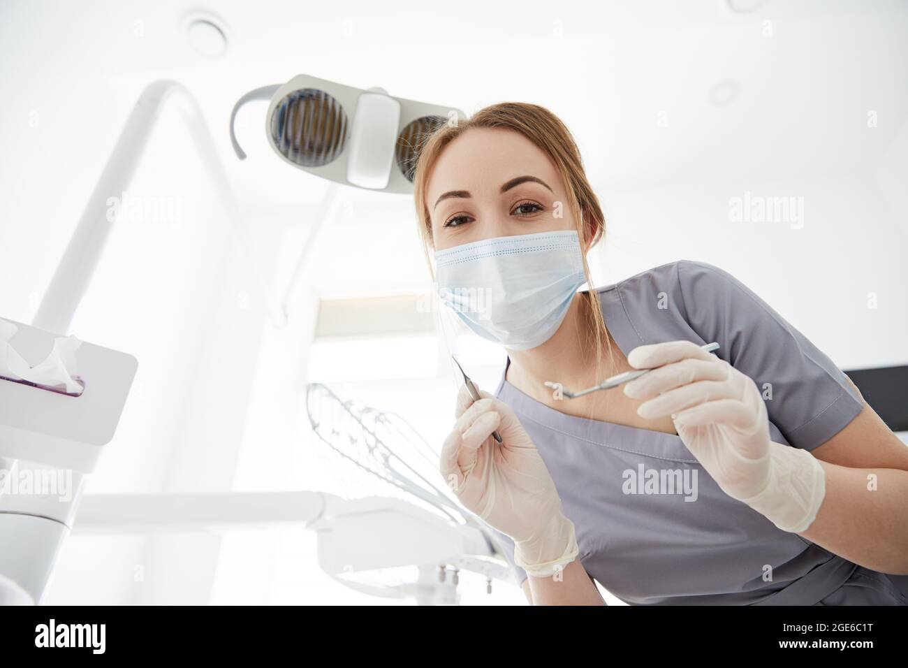 Giovane medico dentista in piedi in ufficio con le forniture dentali nelle sue mani. Foto Stock