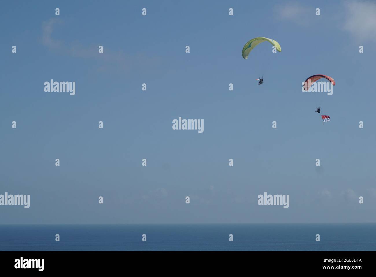 Badung, Bali, Indonesia. 17 agosto 2021. Due parapendio visto come portano la bandiera durante lo spettacolo. La Federazione Nazionale Aerosport (FASI) con l'Aeronautica militare di Bali per la mostra di parapendio porta la bandiera nazionale di 'Merah Putih' (Rosso e Bianco) per commemorare l'Indonesia 76 ° giorno di Indipendenza a Riug Hills, Benoa. La Repubblica di Indonesia proclama il giorno dell'Indipendenza il 17 agosto 1945. (Immagine di credito: © Dicky BisinglasiZUMA Press Wire) Foto Stock