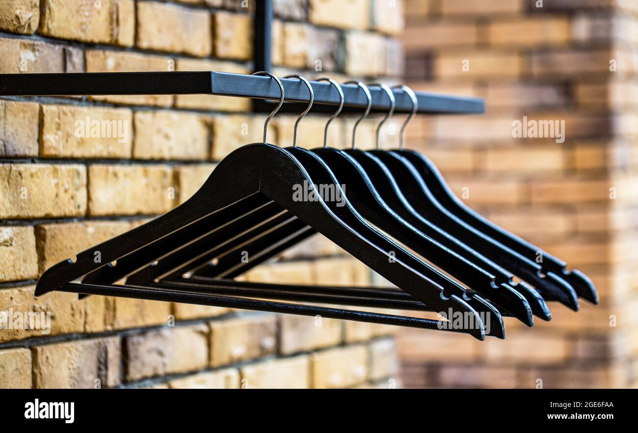 Diversi tipi di appendiabiti alla moda. Appendiabiti in legno. Molti hangers neri di legno su un'asta. Concept del negozio, vendita, design, appendiabiti vuoti. Cappotto di legno Foto Stock