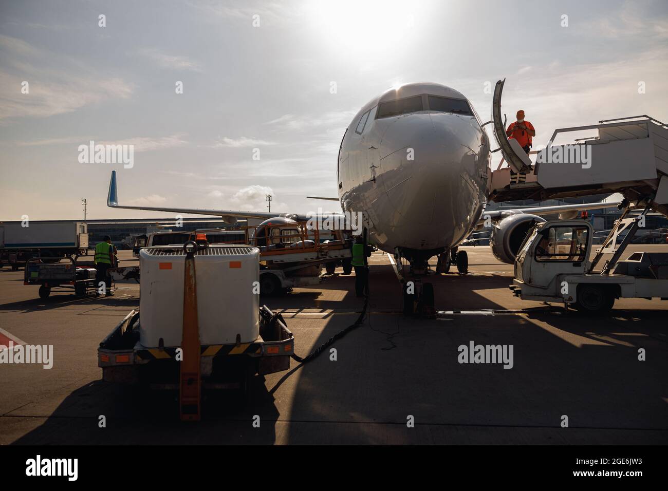 Persone in piedi vicino a un grande aereo moderno, preparandolo per l'imbarco in aeroporto hub di giorno Foto Stock