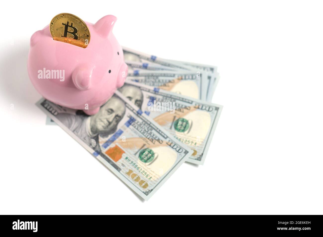 Bitcoin Piggy banca e pacchetto di centinaia di dollari bollette sparse su sfondo bianco. Foto Stock