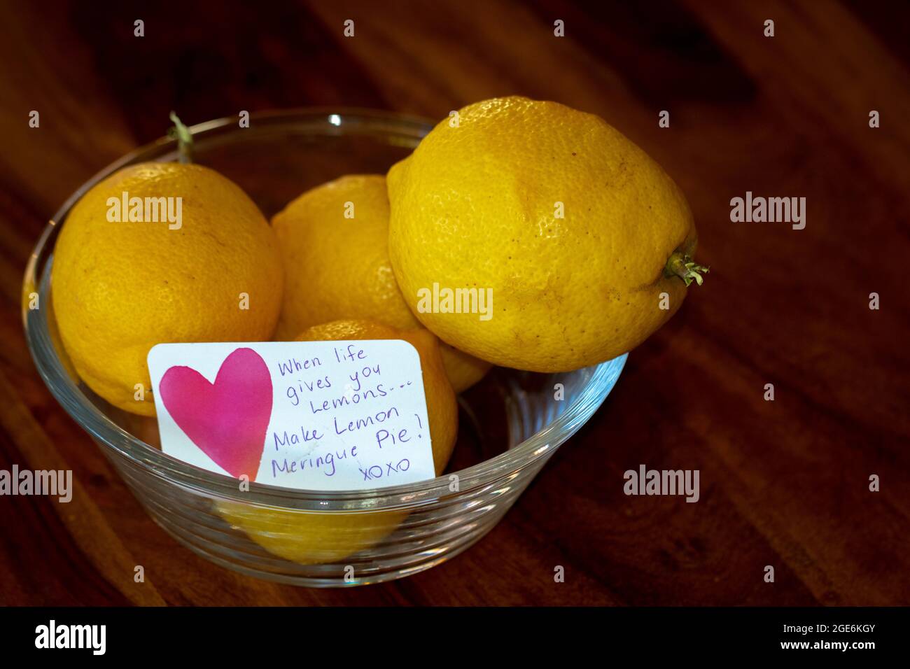 Limoni gialli in una ciotola di vetro con nota, quando la vita vi dà limoni... fate la torta di meringa di limone! Foto Stock