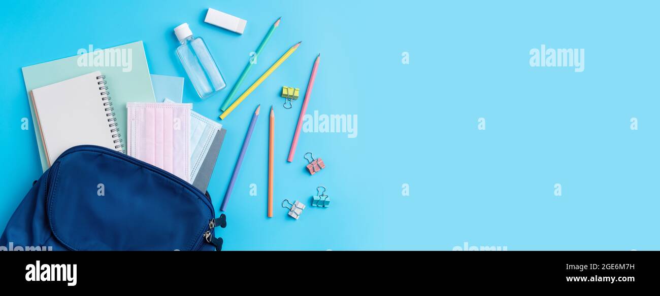 Vista dall'alto dello zaino blu con cancelleria da scuola su sfondo blu, concetto di design di ritorno a scuola. Foto Stock