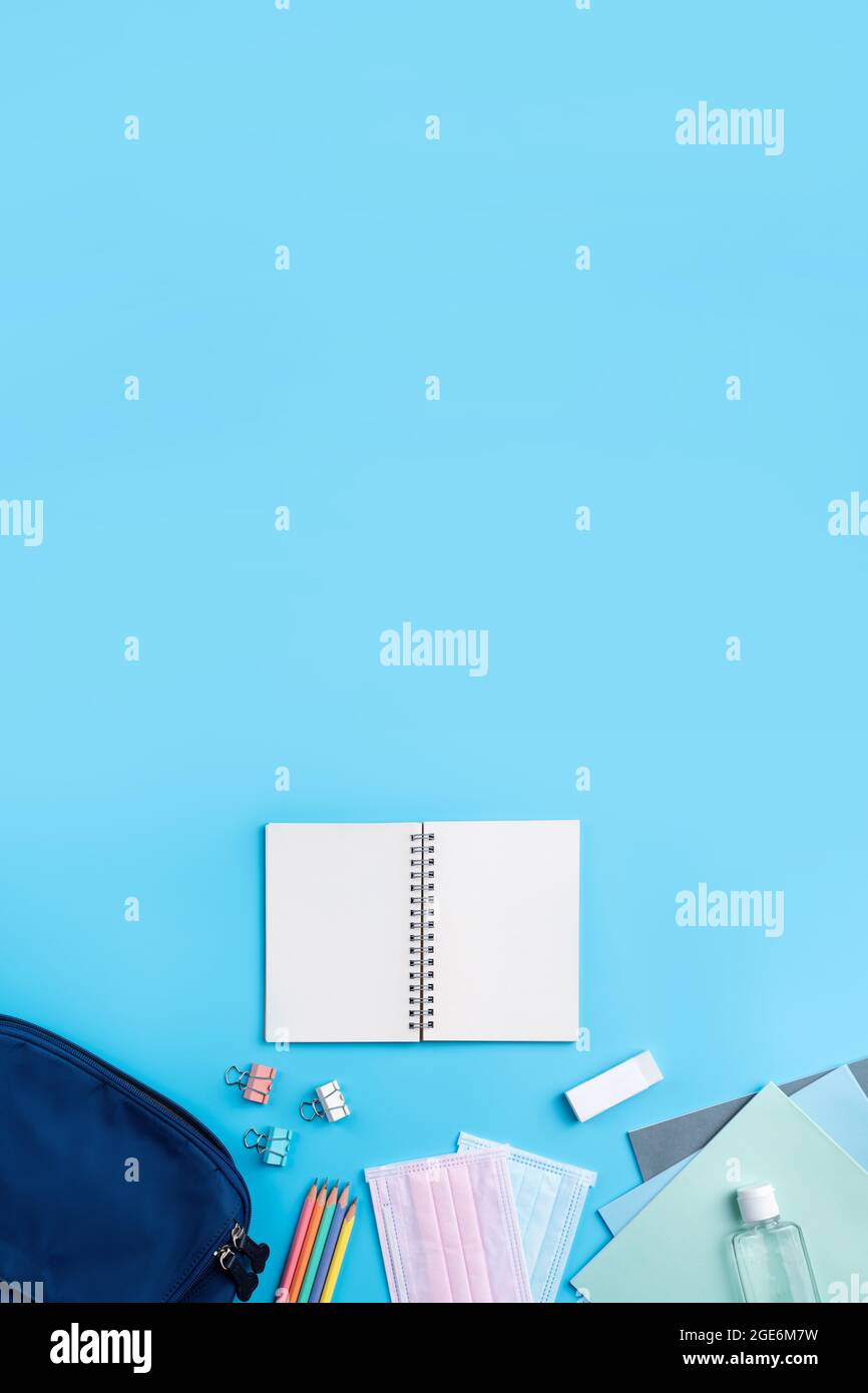 Vista dall'alto dello zaino blu con cancelleria da scuola su sfondo blu, concetto di design di ritorno a scuola. Foto Stock