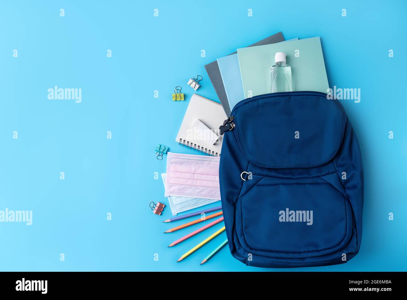 Vista dall'alto dello zaino blu con cancelleria da scuola su sfondo blu, concetto di design di ritorno a scuola. Foto Stock