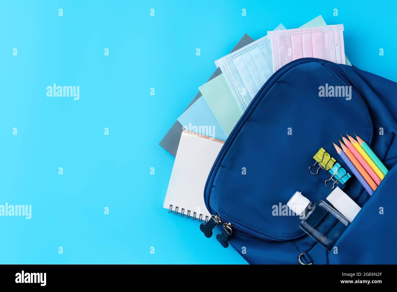 Vista dall'alto dello zaino blu con cancelleria da scuola su sfondo blu, concetto di design di ritorno a scuola. Foto Stock