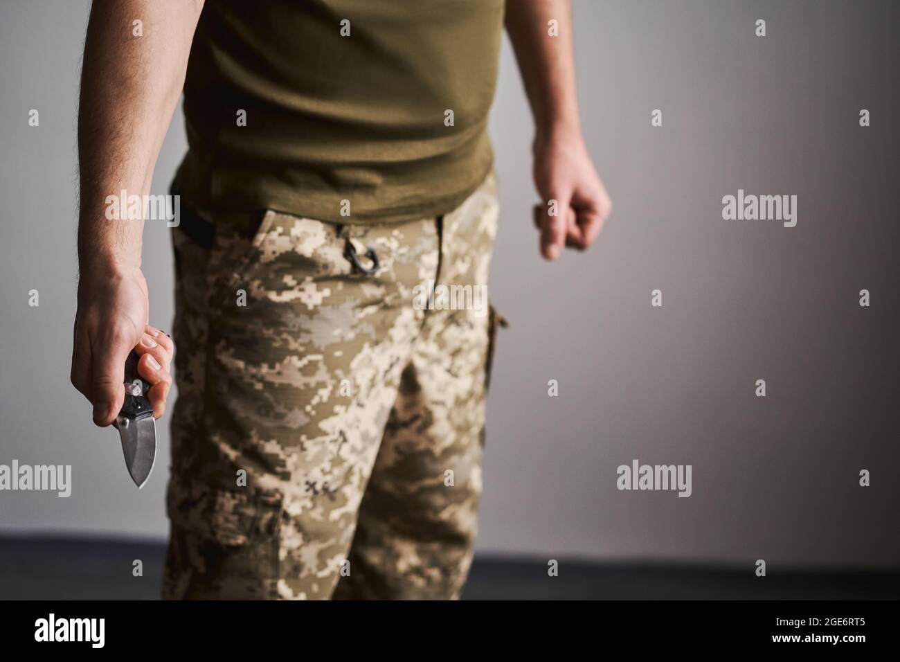 Colpo di sezione media di un uomo militare che tiene pronto un coltello da tasca Foto Stock