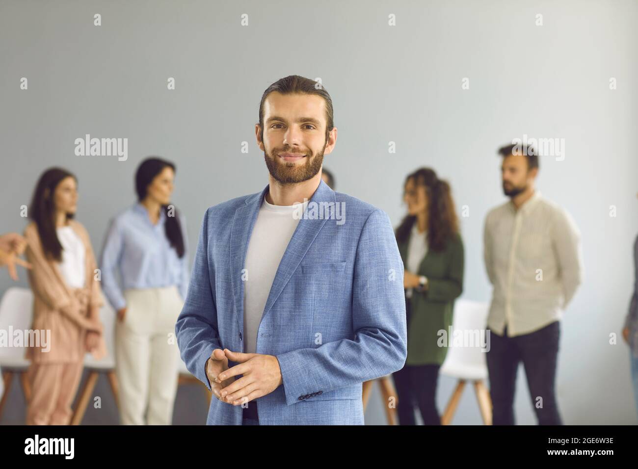 Ritratto di un giovane uomo d'affari sorridente e fiducioso sullo sfondo dei dipendenti. Foto Stock