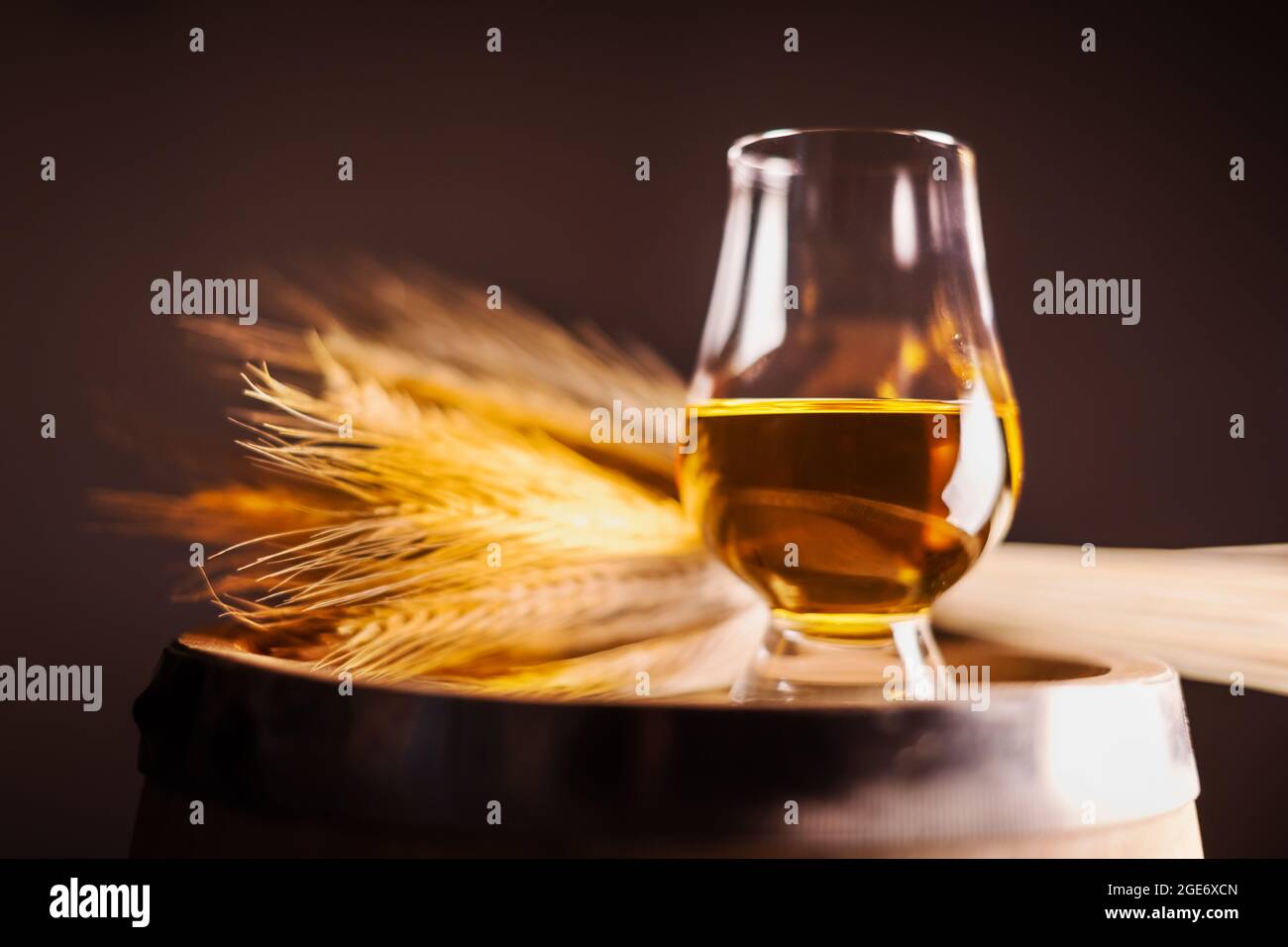 Un bicchiere di whisky sul vecchio barile di quercia con un mazzetto di segale. Tradizionale concetto di distilleria alcolica Foto Stock