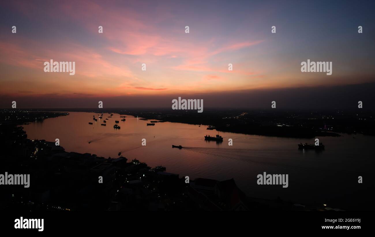 Vista aerea del fiume Chao Phraya e del quartiere della capitale di Samutprakan al tramonto. Spettacolari nuvole e colorati riflessi del cielo al tramonto sul fiume. Foto Stock