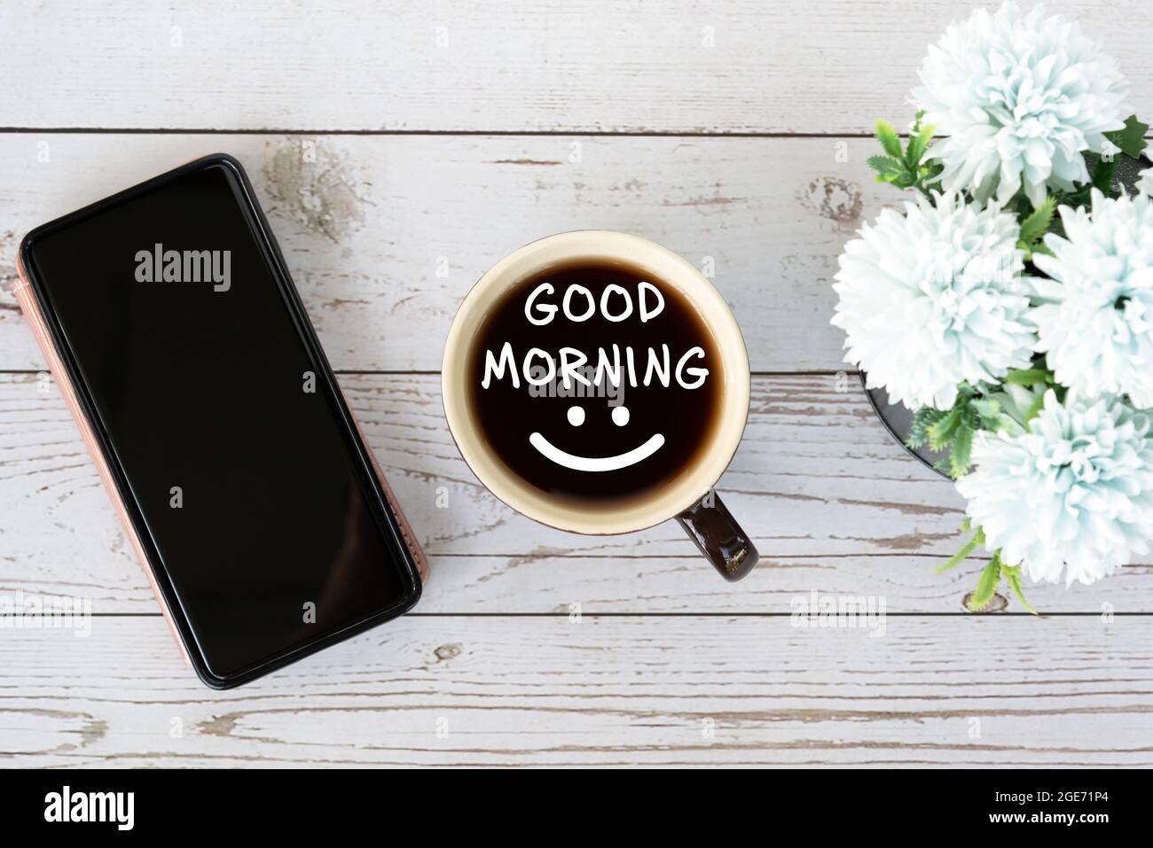 Buon saluto del mattino con una tazza di caffè con smartphone e fiore Foto Stock