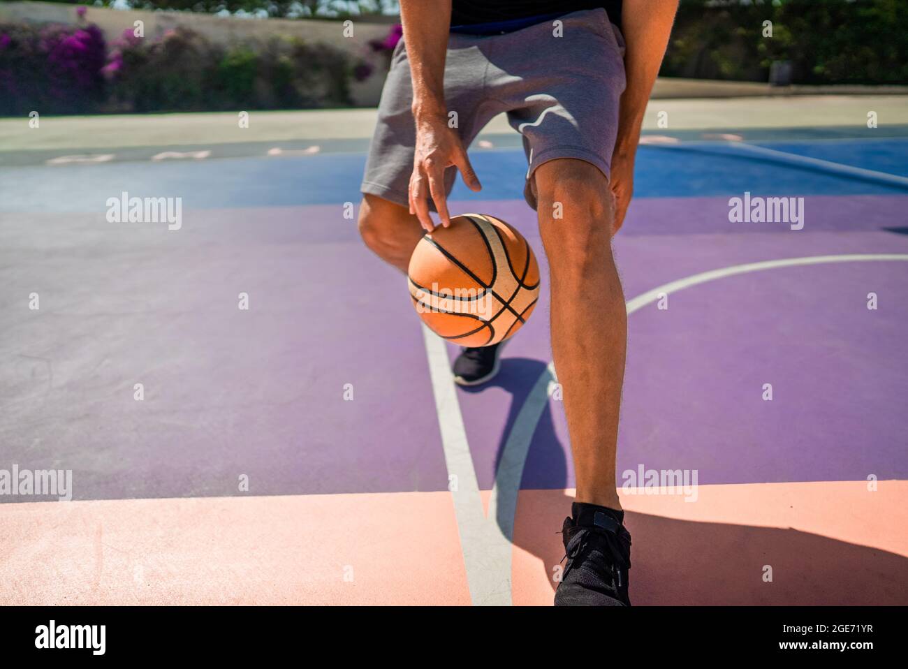 Gambe di un giocatore di basket professionista che dribbling la palla sul campo di pallacanestro. Il gioco è in pieno svolgimento Foto Stock