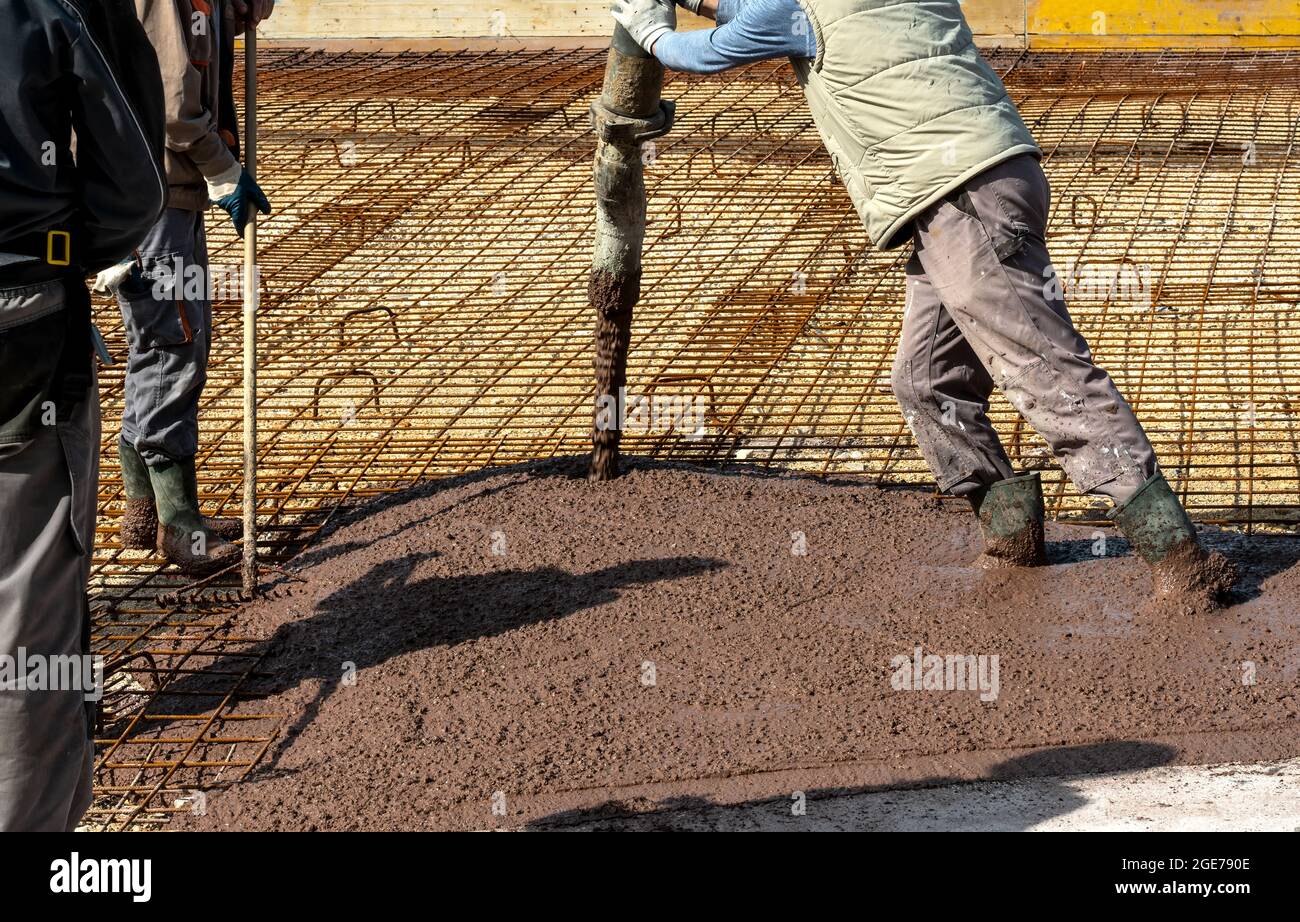 I costruttori lavorano sul cantiere: Versando calcestruzzo marrone per fondazione Foto Stock