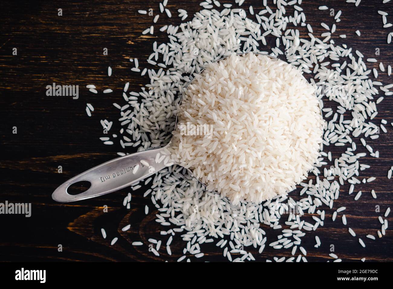 Una coppa di misurazione piena di riso a grani lunghi non cotti: Una coppa di misurazione in acciaio inox riempita con grani di riso bianco crudo Foto Stock