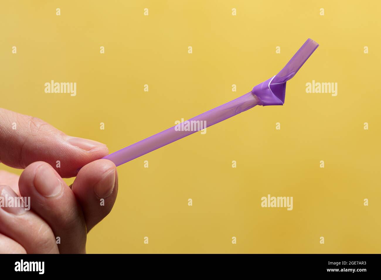 La mano dell'uomo che tiene una paglia con un nodo in essa. Concetto di plastica monouso Foto Stock